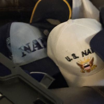 Sale Photo Thumbnail #66: Assortment of U.S. Navy embroidered baseball caps, including a white hat featuring the Navy emblem.