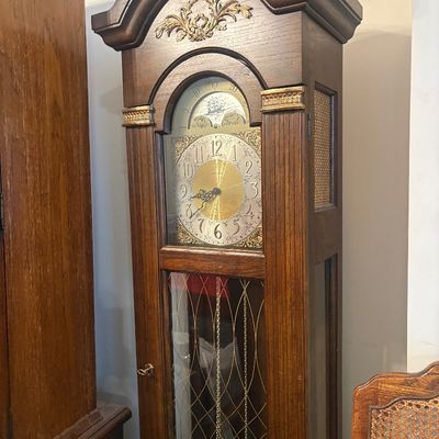 Sale Photo Thumbnail #31: Traditional dark wood grandfather clock featuring an ornate brass face, moon phase dial, and decorative filigree accents.