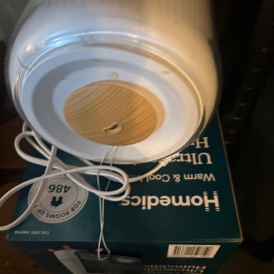 Sale Photo Thumbnail #7: HoMedics warm and cool mist ultrasonic humidifier with wood-look top accent, resting on its original retail box.