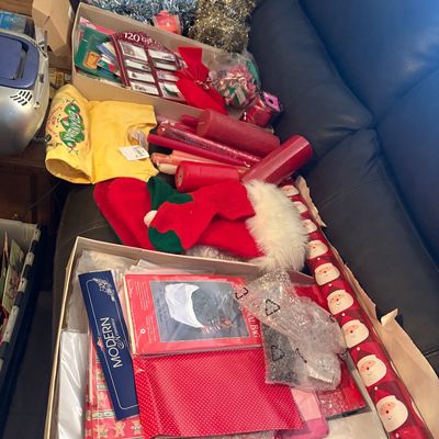 Sale Photo Thumbnail #54: Assortment of holiday wrapping supplies, including Christmas paper rolls, gift tags, red candles, stockings, and tinsel garland.