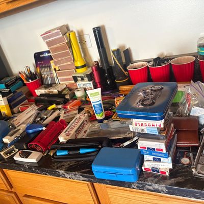 Sale Photo Thumbnail #75: Assortment of household sundries, office supplies, flashlights, playing cards, and small electronics displayed on a kitchen countertop.