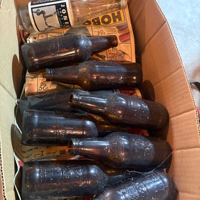 Sale Photo Thumbnail #85: Cardboard box filled with assorted vintage amber and clear glass soda bottles, including a Jones Soda bottle.
