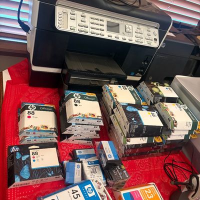 Sale Photo Thumbnail #17: HP OfficeJet Pro all-in-one printer surrounded by multiple boxed and unboxed HP ink cartridges including HP 88, 45, and 23 models.
