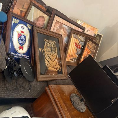 Sale Photo Thumbnail #32: Collection of framed wall art, including an Old Style beer mirror and a velvet tiger print, arranged near exercise equipment and electronics.