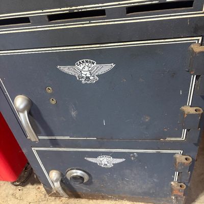 Sale Photo Thumbnail #41: Heavy-duty Cannon dual-compartment steel safe with combination lock and keyholes, showing surface wear and age.