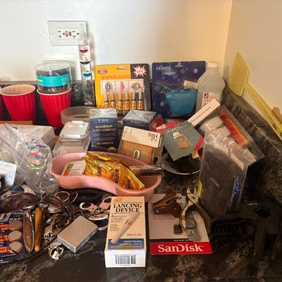 Sale Photo Thumbnail #74: Assortment of household sundries, office supplies, and personal care items arranged on a countertop.