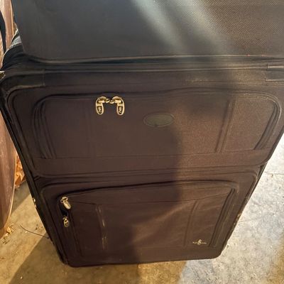 Sale Photo Thumbnail #115: Stack of black softside rolling suitcases featuring multiple zippered exterior compartments.