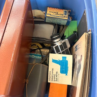 Sale Photo Thumbnail #60: Blue plastic storage bin filled with vintage items, including a Lentar Model 3PZ Super 8 movie camera with manual, vinyl record albums, a 1933 Chicago World's Fair souvenir box, and a brown carrying case.