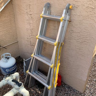 Sale Photo Thumbnail #27: Folded aluminum multi-position telescoping ladder with yellow safety accents leaning against a wall.