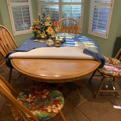 Sale Photo Thumbnail #122: Round light oak dining table set with four matching spindle-back chairs featuring colorful floral seat cushions.