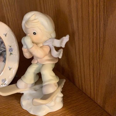 Sale Photo Thumbnail #42: Precious Moments porcelain figurine depicting a young boy skiing, rendered in muted pastel tones.