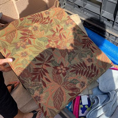 Sale Photo Thumbnail #30: Padded outdoor chair cushion featuring a woven tropical floral pattern in shades of rust, green, and gold, complete with corner tie strings.