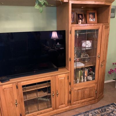Sale Photo Thumbnail #38: Traditional honey oak entertainment center with leaded glass door cabinets, brass hardware, and integrated display shelving, shown with flat-screen television.