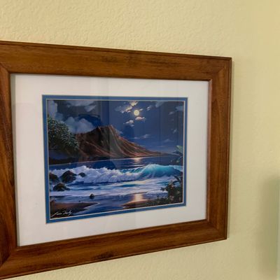 Sale Photo Thumbnail #105: Framed artwork by Lance Fairly depicting Diamond Head and crashing waves under a full moon, set in a wood frame with a white mat.