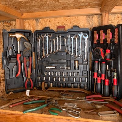 Sale Photo Thumbnail #17: Comprehensive Task Force hand tool set in a molded plastic case, alongside additional loose tools including pliers and shears on a wooden workbench.