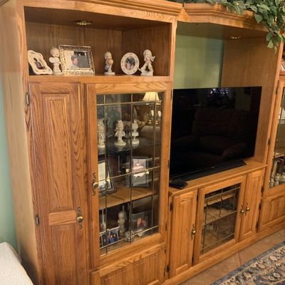 Sale Photo Thumbnail #37: Large 1990s honey oak entertainment center featuring glass display cabinets with leaded accent doors, built-in overhead lighting, and ample lower storage.