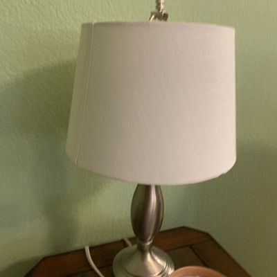 Sale Photo Thumbnail #46: Modern brushed nickel table lamp featuring a tapered metal body and a white fabric drum shade.