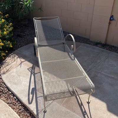 Sale Photo Thumbnail #14: Vintage beige wrought iron and mesh patio chaise lounge with rear wheels and scrolling armrests.