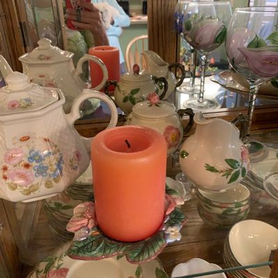 Sale Photo Thumbnail #55: Collection of floral ceramic teaware, hand-painted wine glasses, and a pink pillar candle displayed inside a wooden curio cabinet.