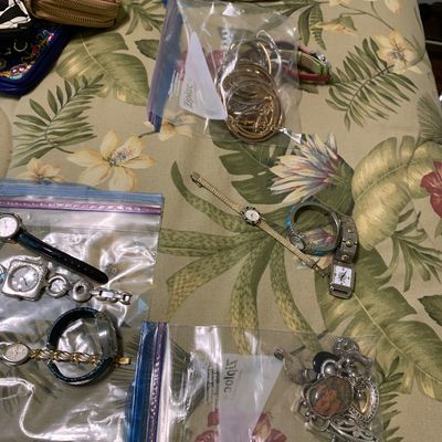 Sale Photo Thumbnail #99: Collection of women's wristwatches, costume jewelry, and wallets packaged in plastic bags on a floral comforter.