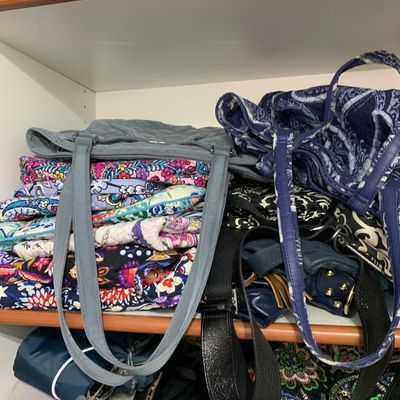 Sale Photo Thumbnail #111: A collection of quilted fabric and leather handbags, including several Vera Bradley printed shoulder bags, stacked on closet shelves.