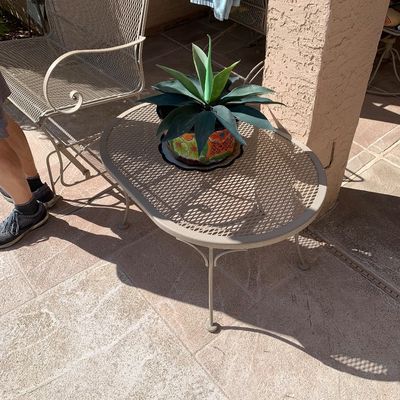 Sale Photo Thumbnail #9: Oval expanded metal mesh patio coffee table with a light beige finish, holding a potted agave plant in a colorful Talavera pot.