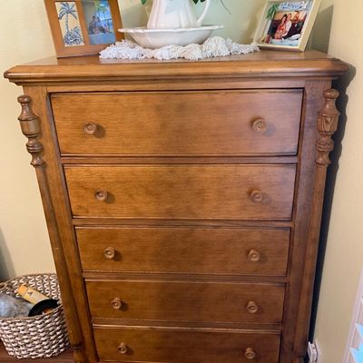 Sale Photo Thumbnail #94: Traditional five-drawer oak dresser featuring turned side accents, round wood knobs, and a bun foot base.