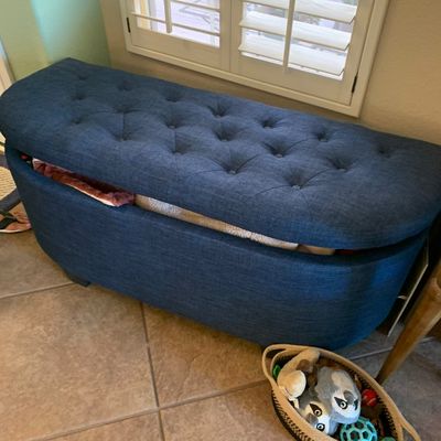 Sale Photo Thumbnail #34: Contemporary blue fabric upholstered storage ottoman with a button-tufted top, shown propped slightly open.