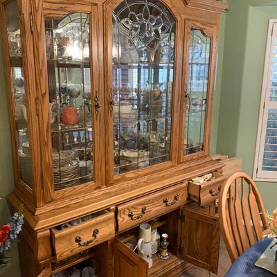 Sale Photo Thumbnail #47: Traditional golden oak china cabinet featuring leaded glass doors, lower drawers, and base storage cabinets.