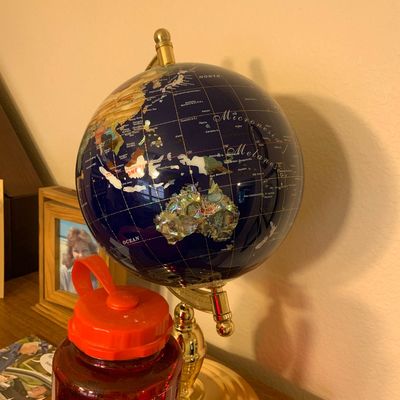 Sale Photo Thumbnail #92: Lapis lazuli gemstone desk globe with mother-of-pearl and inlaid stone continents, set on a polished brass stand.