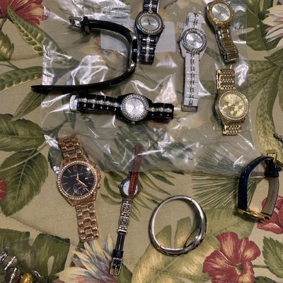 Sale Photo Thumbnail #96: Assortment of modern women's fashion wristwatches including Michael Kors and Brighton brands, displayed with metal link and leather straps on a floral surface.