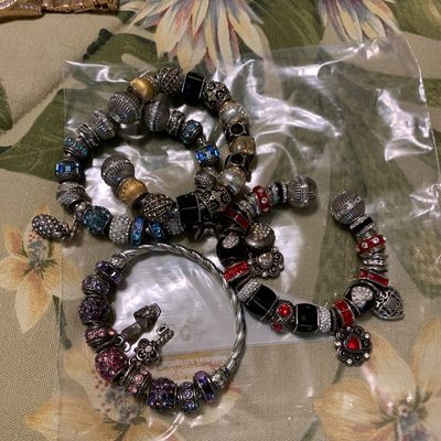 Sale Photo Thumbnail #95: Collection of charm bracelets in a plastic bag featuring colorful glass beads, rhinestone accents, and silver-tone dangle charms, shown alongside wristwatches.