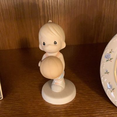 Sale Photo Thumbnail #41: Vintage Precious Moments porcelain figurine featuring a young boy holding a basketball, displayed on a wooden shelf.