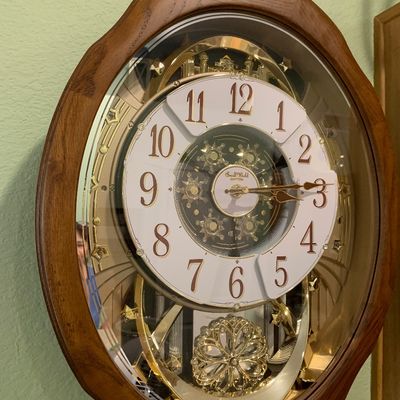Sale Photo Thumbnail #63: Rhythm Small World musical motion wall clock in a wooden oval frame with ornate gold-tone accents.
