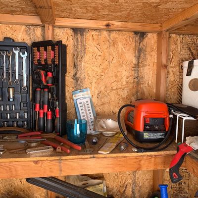 Sale Photo Thumbnail #22: Workshop shelf with a black blown-mold tool set, portable red air compressor, indoor/outdoor thermometer, and various hand tools.