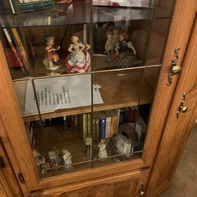 Sale Photo Thumbnail #44: Oak curio cabinet with leaded glass door panels, housing various porcelain figurines, framed photos, and books.