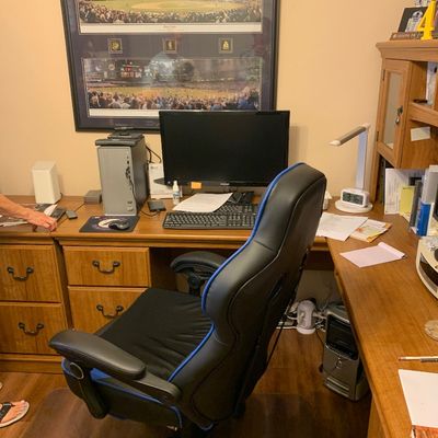 Sale Photo Thumbnail #91: Home office setup including an L-shaped wooden desk with drawers, black and blue gaming chair, computer monitor, towers, and framed baseball stadium artwork.