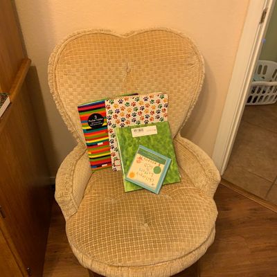 Sale Photo Thumbnail #89: Vintage heart-shaped upholstered accent chair with textured cream fabric, holding an assortment of folders and children's books.