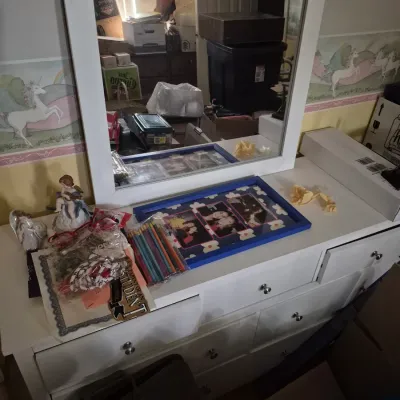 Sale Photo Thumbnail #60: White wooden dresser with framed mirror, displaying various small items including figurines, colored pencils, and picture frames.