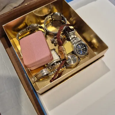 Sale Photo Thumbnail #73: Assortment of vintage wristwatches and a small pink jewelry case, including Seiko and various metal and leather strap models, presented in a gold-tone box.