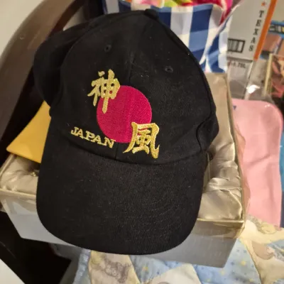 Sale Photo Thumbnail #57: Black baseball cap featuring an embroidered red rising sun graphic with gold Japanese characters and "JAPAN" text.