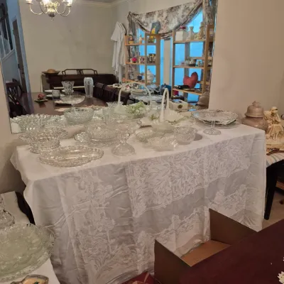 Sale Photo Thumbnail #5: Large collection of vintage pressed and cut glassware displayed on a tablecloth-covered dining table, including bowls, cake stands, and serving platters.