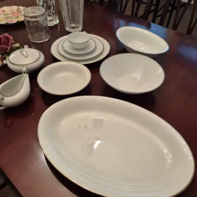 Sale Photo Thumbnail #64: Collection of white porcelain tableware featuring platinum trim, including serving platters, bowls, a creamer, sugar bowl, and place setting pieces, along with clear glass vases.