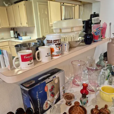Sale Photo Thumbnail #17: Collection of household goods including novelty ceramic mugs, glassware, a boxed Shiatsu massage pillow, and miniature tagine dishes.