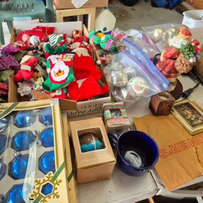 Sale Photo Thumbnail #26: Collection of vintage Christmas decorations, featuring boxed blue glass ornaments, loose felt stockings, clear glass baubles in plastic bags, and a Santa figurine.