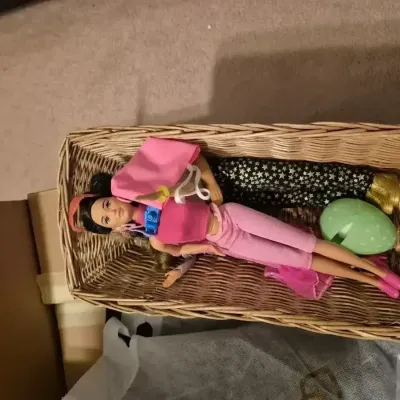 Sale Photo Thumbnail #52: Wicker storage basket containing two fashion dolls with clothing, accessories, and a plastic egg.