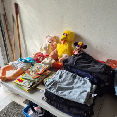 Sale Photo Thumbnail #28: Folding table displays vintage character plush toys including Big Bird and Minnie Mouse, along with baby dolls, children's books, and folded clothing.