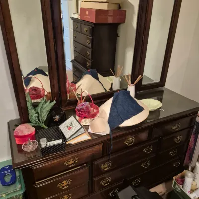 Sale Photo Thumbnail #45: Traditional dark wood triple-mirror vanity dresser with brass bail pulls, holding various small decor items, small boxes, and a conical hat.