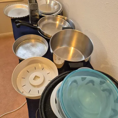 Sale Photo Thumbnail #70: Assorted vintage cookware and bakeware, including stainless steel pots, aluminum pie pans, a metal box grater, and a speckled enamel roaster.