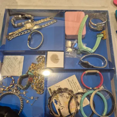 Sale Photo Thumbnail #72: Assorted costume jewelry and wristwatches displayed inside a compartmentalized tray. Includes gold-tone chains, silver-tone bangles, beaded bracelets, and various fashion watches.